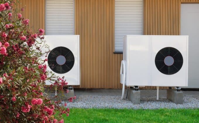 Highlighting high-efficiency air source heat pumps, this image showcases their installation on the exterior of a contemporary home, tapping into green electricity for sustainable heating.