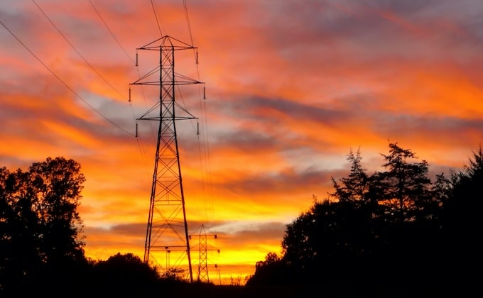 Power transmission tower against pink and orange sunset