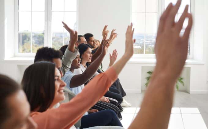 A group of people listening and raising hands